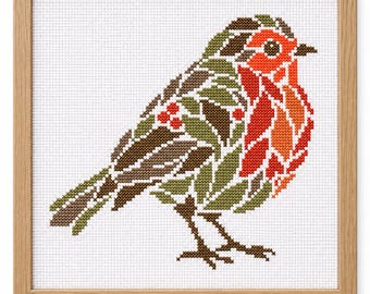May include: A cross-stitch pattern of a robin bird in a light wood frame. The bird is composed of green leaves, brown feathers, and bright red berries on its chest and wing. The design is stitched onto white Aida fabric with a grid texture.