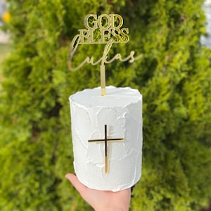 May include: White cake with gold cross and topper that says "God Bless Lukas"