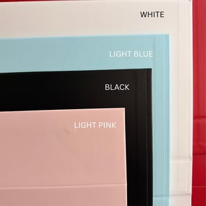 May include: A stack of rectangular boxes in various colors, including red, white, light blue, black, and light pink. Each box is labeled with its corresponding color name in white text, providing a clear visual guide to the available color options.