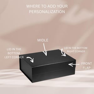May include: A rectangular black gift box with a lid and front flap. Text indicates personalization areas: WHERE TO ADD YOUR PERSONALIZATION, MIDLE, LID IN THE BOTTOM LEFT CORNER, LID IN THE BOTTOM RIGHT CORNER, and FRONT FLAP, with arrows pointing to each.