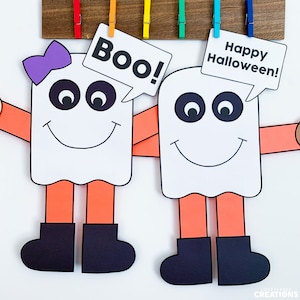 Puede incluir: Dos fantasmas amigables con piernas naranjas y zapatos negros. Un fantasma tiene un lazo morado y dice "¡Boo!" El otro fantasma dice "¡Feliz Halloween!"