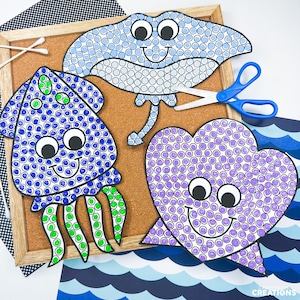 May include: Three paper cutouts of a stingray, a squid, and a seashell, each decorated with colorful circular stickers. The stingray is light blue, the squid is blue and green, and the seashell is purple. Each figure features large googly eyes.