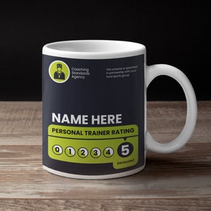 May include: A white ceramic mug with a black and yellow design. The mug features the text "Coaching Standards Agency", "NAME HERE", "PERSONAL TRAINER RATING", and "EXCELLENT". There are five numbered circles, with the number 5 highlighted in yellow.