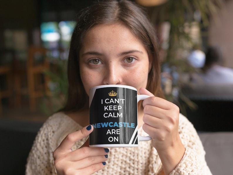 Puede incluir: Taza de cer&aacute;mica blanca con fondo negro y corona dorada. El texto en la taza dice "I can't keep calm Newcastle are on".