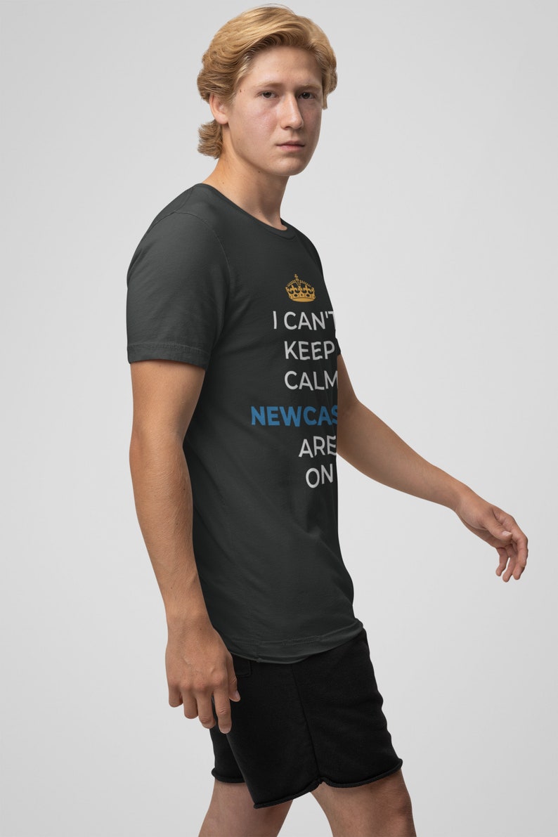 May include: A black t-shirt with a white graphic that says "I can't keep calm Newcastle are on" with a gold crown above the word "can't".
