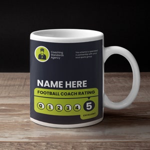 Puede incluir: Una taza de cerámica blanca con un diseño negro y verde. La taza presenta el texto "NAME HERE" y "FOOTBALL COACH RATING" con una escala de calificación de 0 a 5. El número 5 está resaltado en verde y el texto "EXCELLENT" está debajo.