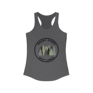 May include: A dark gray racerback tank top with a circular graphic featuring pine trees in shades of green and gray. The text "SNORT PINES NOT LINES" is printed around the trees in a black font. The tank top has a scoop neck and a racerback design.