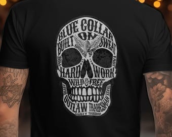 May include: Black t-shirt featuring a skull design with the words "Blue Collar," "Built," "Hard Work," and "Outlaw Tradesman" in a white, stylized font. The design includes an eagle and the words "Wild & Free."