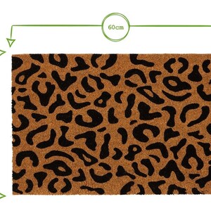 May include: A brown coir doormat with a black leopard print design. The doormat measures 60 cm by 40 cm.