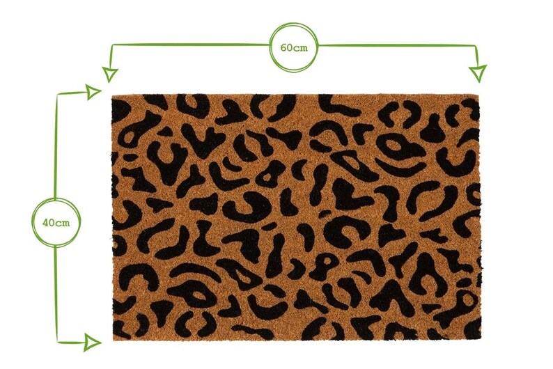 May include: A brown coir doormat with a black leopard print design. The doormat measures 60 cm by 40 cm.