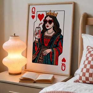 May include: A framed wall art print depicting a playing card queen wearing a gold crown and heart-shaped sunglasses, holding a silver can labeled Diet Coke. The illustration features a red, teal, and white color palette with a classic card design.