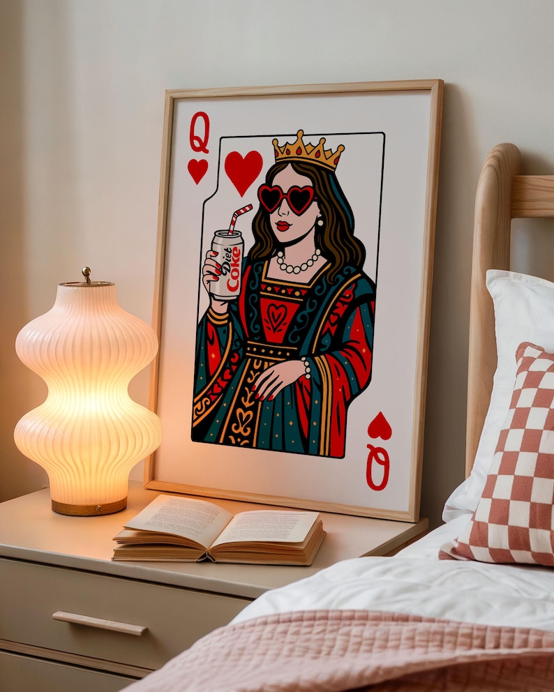 May include: A framed wall art print depicting a playing card queen wearing a gold crown and heart-shaped sunglasses, holding a silver can labeled Diet Coke. The illustration features a red, teal, and white color palette with a classic card design.