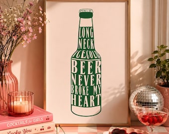 Może przedstawiać: Oprawiony wydruk z zielonym wzorem butelki piwa i napisem "LONG NECK ICE COLD BEER NEVER BROKE MY HEART". Obraz jest umieszczony na różowym tle, ze złotą ramą. Scena obejmuje książki, wiśnie i okulary przeciwsłoneczne w kształcie serca.