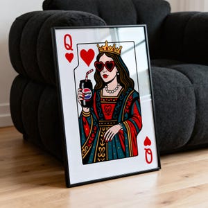 May include: Framed art print featuring a playing card design of the Queen of Hearts. The queen wears heart-shaped sunglasses and holds a Pepsi can with a straw. The artwork is in a black frame and set against a neutral background.