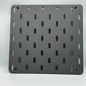Könnte beinhalten: Eine graue Metall-Lochwand mit einem Raster aus gleichmäßig verteilten Löchern. Die Lochwand ist zum Aufhängen von Werkzeugen, Zubehör oder anderen Gegenständen gedacht.
