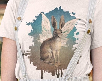 May include: A white t-shirt with a graphic of a brown rabbit with white wings against a blue and white watercolor background.