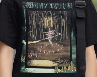 May include: Black t-shirt with a graphic print of a fairy dancing in a forest with mushrooms and rabbits. The graphic is surrounded by a green, yellow, and black frame.