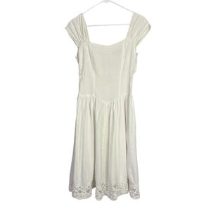 May include: A white dress with a square neckline and cap sleeves hangs on a white hanger. The dress features a fitted bodice, a flared skirt, and lace trim along the hemline. The dress is made of a lightweight fabric.