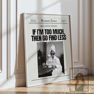 May include: A framed print with a black and white photograph of a woman in a bathrobe and sunglasses, reading and drinking coffee. The print includes the text "Women News" and the quote "IF I'M TOO MUCH, THEN GO FIND LESS."
