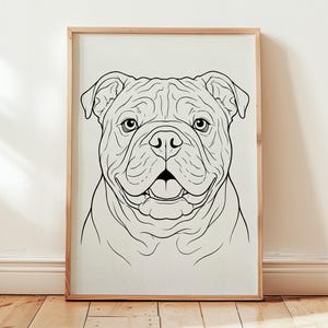 Puede incluir: Una lámina de arte enmarcada que presenta un dibujo de líneas en blanco y negro de la cara de un bulldog. La ilustración muestra al perro con la frente arrugada, orejas caídas y la boca abierta, centrada en un marco de madera clara.