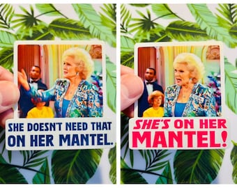 May include: Two stickers showing a woman in a patterned jacket. One sticker says "SHE DOESN'T NEED THAT ON HER MANTEL." The other sticker says "SHE'S ON HER MANTEL!" Both stickers have a white border.
