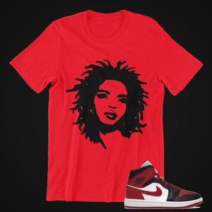May include: Red t-shirt with a black silhouette of a woman's face with curly hair.  The t-shirt is paired with black and red Air Jordan 1 Mid sneakers with a white swoosh.