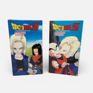 Könnte beinhalten: Zwei Dragon Ball Z Sammlerboxen. Die Boxen sind blau mit dem Dragon Ball Z Logo und zeigen Illustrationen von Android 17 und 18. Eine Box trägt die Aufschrift "Androids Assassins", die andere "Androids Invincible".