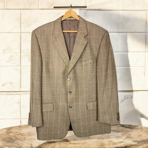 May include: A brown plaid blazer with a single-breasted closure and four buttons. The blazer has a classic fit and a subtle herringbone pattern.