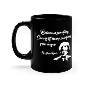 May include: Black ceramic coffee mug with a white silhouette of a man and a quote that reads "Believe in something. Even if it means sacrificing your dangus. -Dr. Steve Brule"