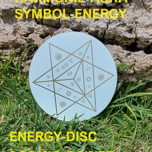 Könnte beinhalten: Eine kreisförmige hellblaue Scheibe mit einem geometrischen sechsstrahligen Sternmuster und verschiedenen kleinen, braun gravierten Spiral- und Kreissymbolen. Der Text HARMONIE-AURA SYMBOL-ENERGY und ENERGY-DISC COSMIC-POWER ist in Gelb aufgedruckt.
