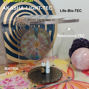 May include: A clear acrylic display stand with a circular base and a top shelf, holding two small bottles. A large, circular design with gold and blue accents is in the background. The text "AKASHA-CUBE", "Elysium-Star", and "AKASHA-LIGHT-TEC" are visible.