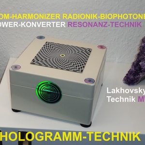 May include: A white box with a black and white checkered pattern on the top. The box has a green light on the front and the text "ROOM-HARMONIZER RADIONIK-BIOPHOTONEN POWER-KONVERTER RESONANZ-TECHNIK Lakhovsky- Technik MWO HOLOGRAMM-TECHNIK" on the front and bottom.
