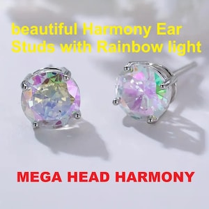 May include: A pair of silver ear studs, each featuring a large, round, iridescent gemstone. The gemstones shimmer with a rainbow effect. The image text reads "beautiful Harmony Ear Studs with Rainbow light" and "MEGA HEAD HARMONY".