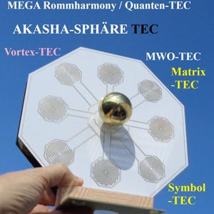 Può includere: Un dispositivo ottagonale bianco con una sfera dorata al centro, tenuto contro un cielo blu. Il dispositivo presenta motivi a spirale e testo come "AREA-IMPULS 100 QM", "AKASHA-SPHÄRE TEC" e altri termini tecnici. È montato su una base di legno.