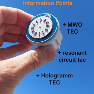 Puede incluir: Un dispositivo electrónico circular con un borde azul y un centro blanco que presenta un anillo de pequeños componentes rojos. El texto dice: Rife-Frequencies Generator mit 30 Hz Programme, 100 Akasha Matrix Light Information Points, + MWO TEC, + resonant circuit tec, + Hologramm TEC.