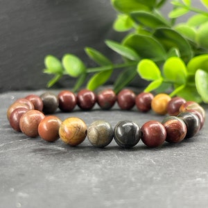 May include: A bracelet made of brown, black and white stone beads. The beads are round and have a natural, polished finish.