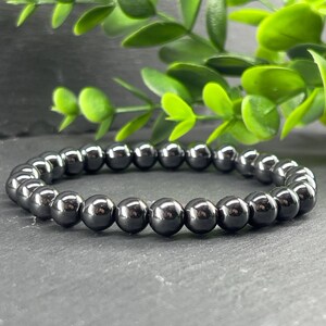 May include: A black beaded bracelet made of round, smooth, polished hematite stones.