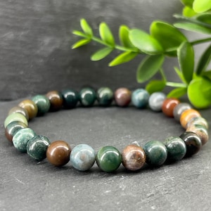May include: A green, brown and red gemstone bracelet with round beads.