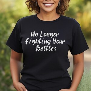 May include: Black t-shirt with white text that reads "No Longer Fighting Your Battles".