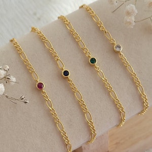 Può includere: Quattro braccialetti a catena dorati con un piccolo accento di pietra preziosa. Le pietre preziose sono rosse, blu, verdi e chiare.