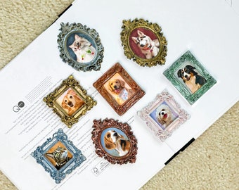 May include: A collection of eight miniature ornate frames containing portraits of various dogs and cats. The frames feature intricate, embossed detailing in metallic finishes including gold, bronze, silver, blue, green, and pink, arranged on a white surface.