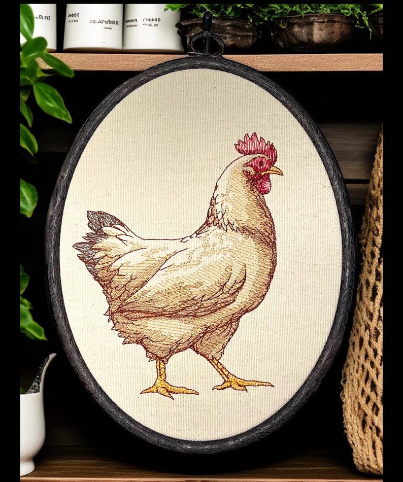 May include: Oval framed embroidery featuring a detailed hen illustration. The hen is depicted in shades of beige and brown with a red comb and yellow legs. The frame is dark with a metal loop for hanging. The background is a neutral canvas.