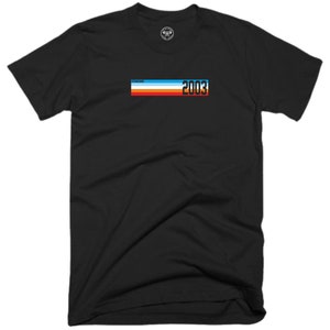 Könnte beinhalten: Schwarzes T-Shirt mit einer Retro-Grafik mit einem mehrfarbigen Streifenmuster und dem Jahr "2003".