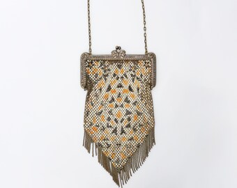 Peut inclure: Un sac à main vintage en maille dorée avec un motif géométrique et des franges. Le sac à main a un fermoir argenté et une bandoulière en chaîne.