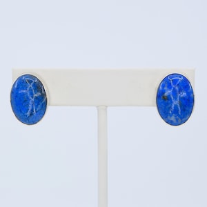 May include: A pair of silver stud earrings with oval-shaped blue lapis lazuli stones.