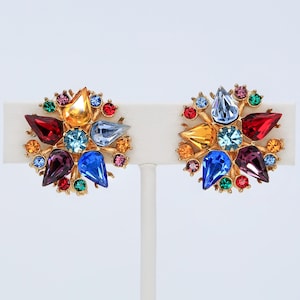 以下が含まれることがあります： カラフルなラインストーンがついたゴールドトーンのクリップ式イヤリングのペア。イヤリングには、赤、青、緑、黄、紫など、さまざまな色が使われています。