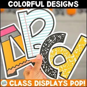 May include: Colorful paper cutouts spelling "PAD" and a pencil, held by a hand. The letters are designed to look like a notebook page and a composition book. The top of the image reads "COLORFUL DESIGNS" and the bottom reads "CLASS DISPLAYS POP!"