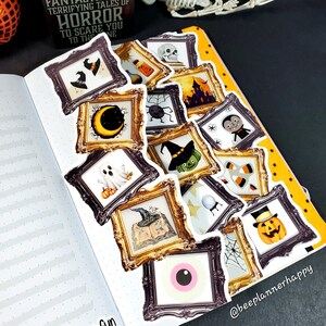 May include: A spread of Halloween-themed stickers in ornate gold frames, including a ghost, pumpkin, witch hat, and vampire. The stickers are arranged on a dotted notebook page with a yellow border. Text on the page reads "HORROR".