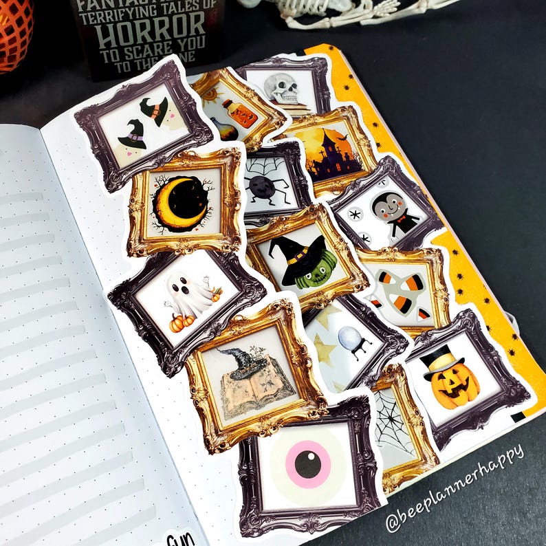 May include: A spread of Halloween-themed stickers in ornate gold frames, including a ghost, pumpkin, witch hat, and vampire. The stickers are arranged on a dotted notebook page with a yellow border. Text on the page reads "HORROR".