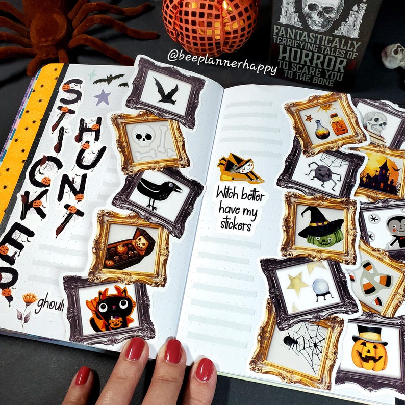 May include: A spread in a planner featuring Halloween-themed stickers. The stickers are framed in ornate gold and black frames, depicting bats, skulls, crows, and pumpkins. The text "Witch better have my stickers" is also visible.